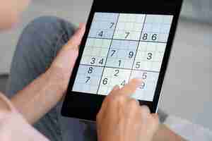 Bezpłatne zdjęcie osoba grająca w sudoku na tablecie