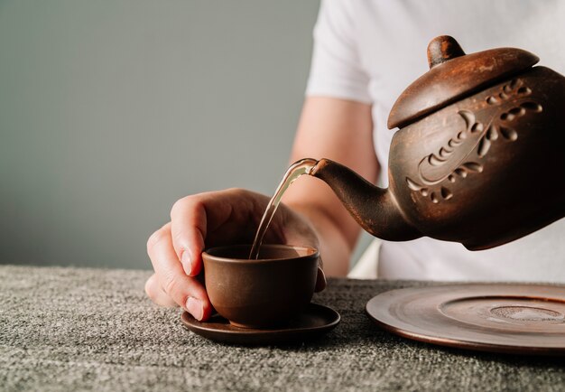 Osoba nalewająca ciepłą herbatę w filiżance