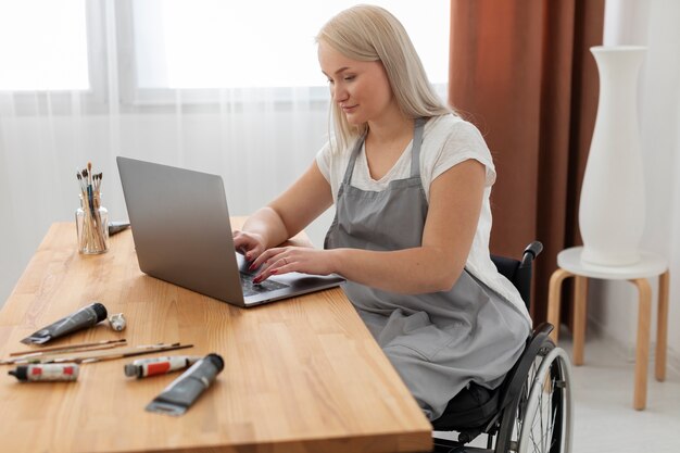 Osoba niepełnosprawna na wózku inwalidzkim pracująca na laptopie