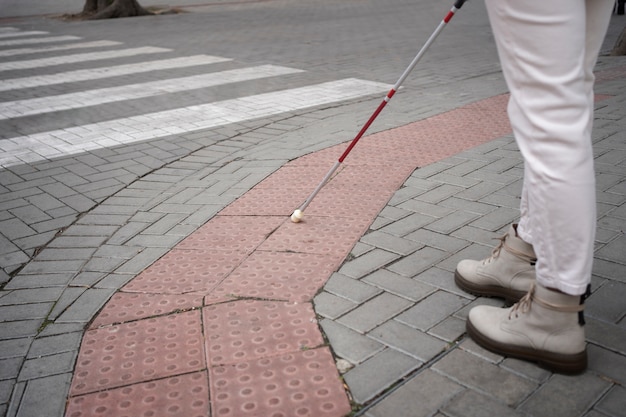 Osoba niewidoma idąca przez miasto ze ślepym kijem