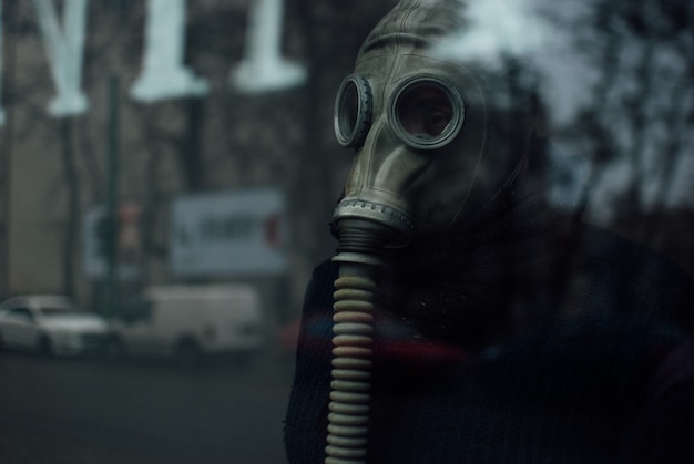Bezpłatne zdjęcie osoba nosząca respirator stojący za szkłem