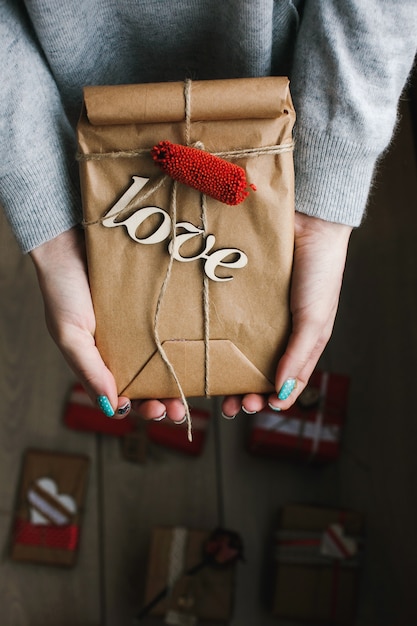 Osoba posiadająca brązową paczkę z napisem &quot;love&quot;