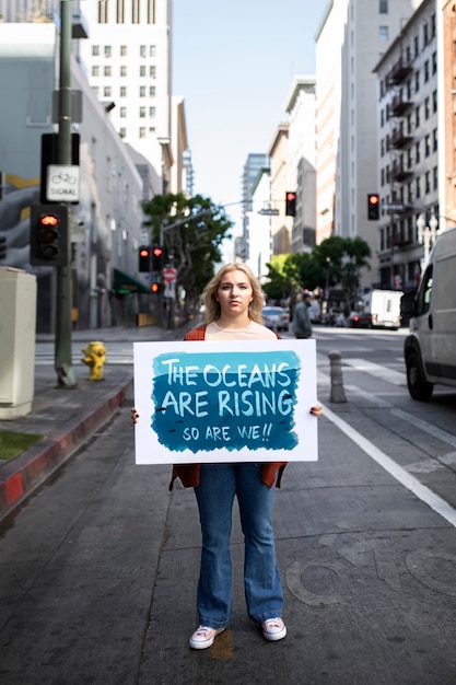 Bezpłatne zdjęcie osoba protestująca z afiszem w mieście na światowy dzień ochrony środowiska