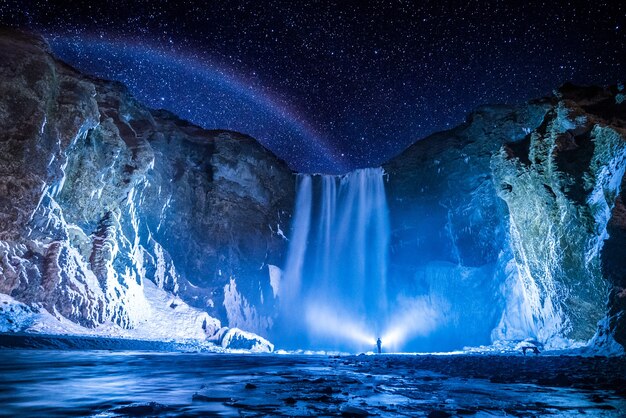 Osoba przed wodospadami w nocy