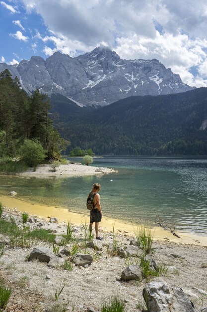 Osoba stojąca na plaży nad jeziorem Eibsee w Niemczech otoczona górami