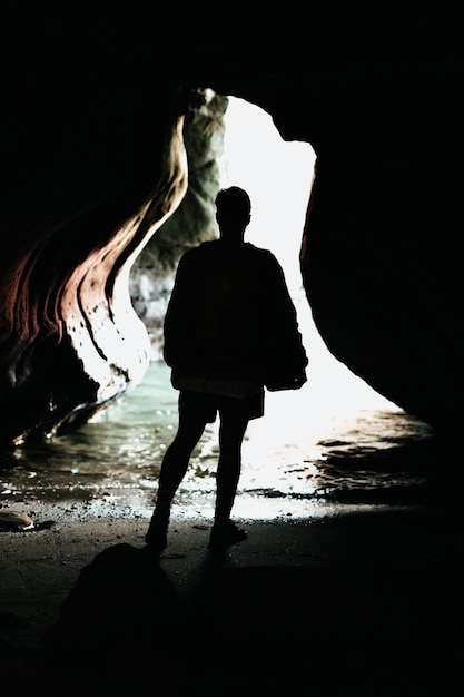 Osoba stojąca przed niebieskim zbiornikiem wodnym w jaskini w ciągu dnia