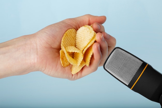 Bezpłatne zdjęcie osoba trzymająca chipsy ziemniaczane blisko mikrofonu dla asmr