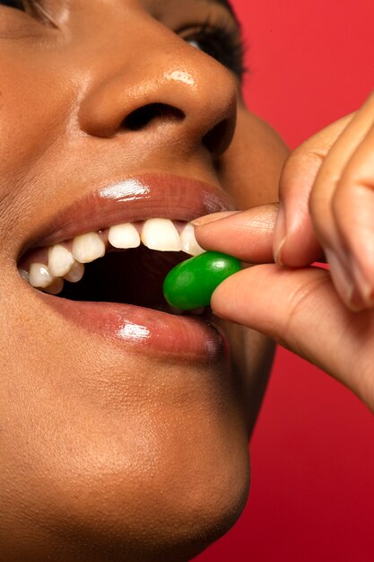 Osoba trzymająca cukierki z żelkami w ustach