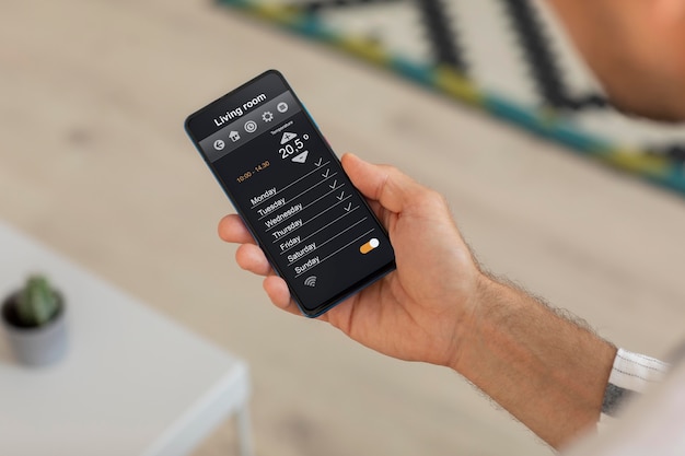 Osoba trzymająca smartfon z aplikacją do domowej automatyzacji