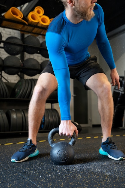 Osoba w sportowej siłowni używająca kettlebells