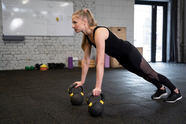 Osoba w sportowej siłowni używająca kettlebells