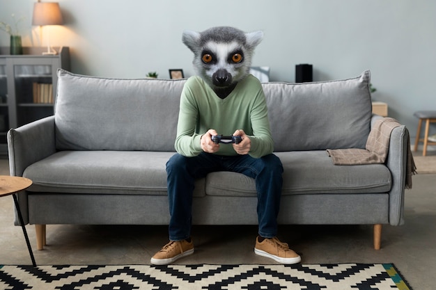 Bezpłatne zdjęcie osoba z głową lemura grająca w gry wideo na kanapie