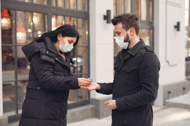 Osoby noszące maskę ochronną stojące na ulicy podczas używania żelu alkoholowego