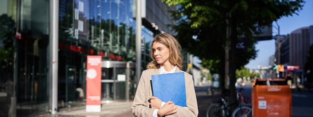 Bezpłatne zdjęcie osoby pracujące i korporacyjne pewna siebie bizneswoman trzyma niebieską teczkę z dokumentami biznesowymi