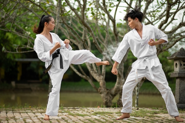 Bezpłatne zdjęcie osoby trenujące razem na świeżym powietrzu do taekwondo