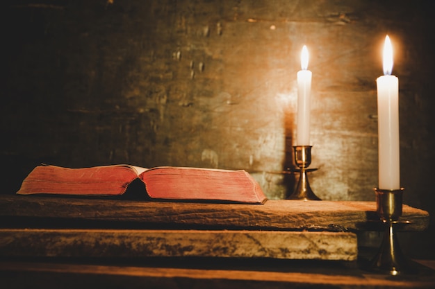 Otwórz Świętą Biblię i świecę na starym dębowym drewnianym stole.