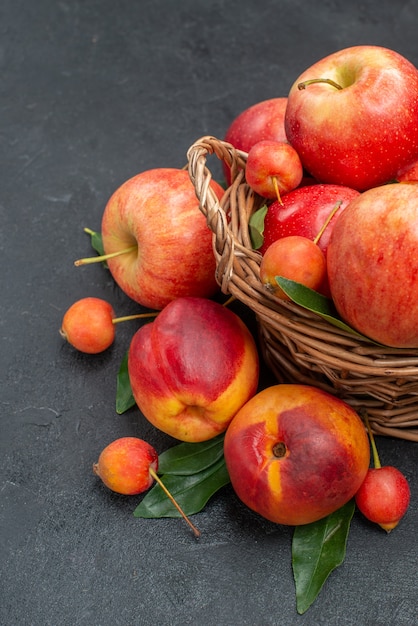 owoce jabłka wiśnie w koszu nektarynka z liśćmi