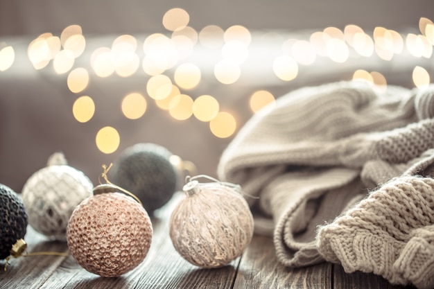 Ozdoby choinkowe na Boże Narodzenie światła bokeh w domu na drewnianym stole ze swetrem na ścianie i dekoracjami.