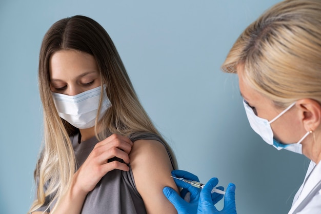 Pacjentka z maską medyczną otrzymująca szczepionkę