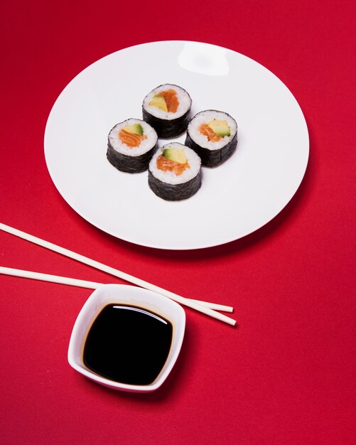 Pałeczki i sos w pobliżu sushi na czerwono
