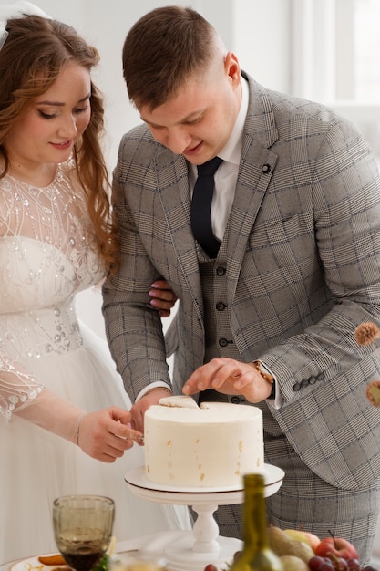 Bezpłatne zdjęcie panna młoda i pan młody kroją tort na weselu
