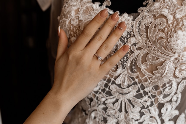 Panna młoda trzyma rękę na wieszanej sukni ślubnej