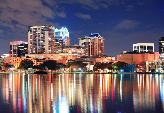 Panorama centrum Orlando nad jeziorem Eola o zmierzchu z miejskimi drapaczami chmur i światłami.