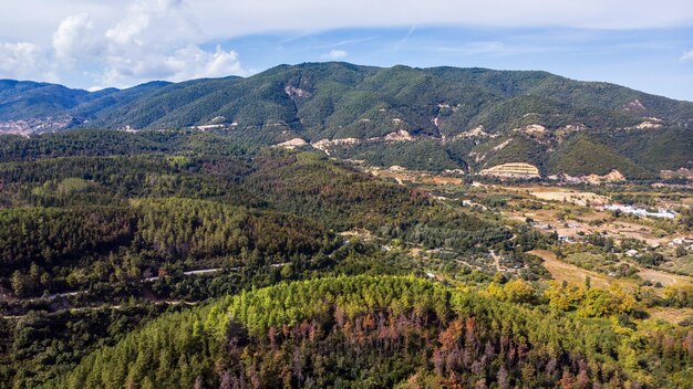 Panorama Grecji z drona, kilka zabudowań w dolinie, wzgórza porośnięte bujną zielenią