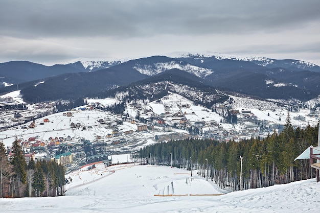 Panorama ośrodka narciarskiego, stok, ludzie na wyciągu, narciarze na stoku wśród zielonych sosen i lanc śnieżnych. Skopiuj miejsce