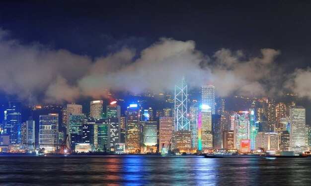 Panoramę Hongkongu w nocy z chmurami nad Victoria Harbour.