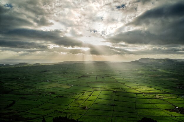 Panoramiczne ujęcie pola agrokulturowego z promieniami słońca wpadającymi przez chmury