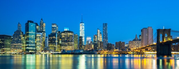 Panoramiczny widok na centrum Nowego Jorku Manhattan o zmierzchu z drapaczami chmur oświetlonymi nad wschodnią rzeką