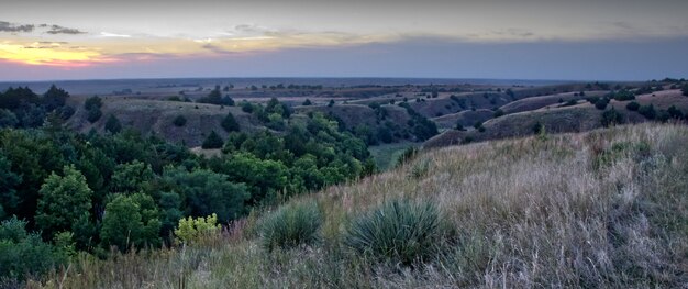 Panoramiczny widok na piękny krajobraz z pasmami górskimi pod niebem zachodzącego słońca