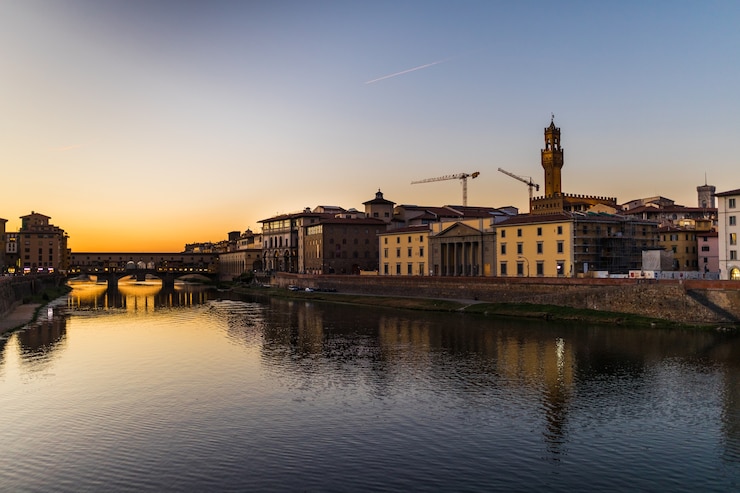 Bezpłatny plik Zdjęcie panoramiczny widok na słynny ponte vecchio z rzeką arno o zachodzie słońca we florencji, włochy