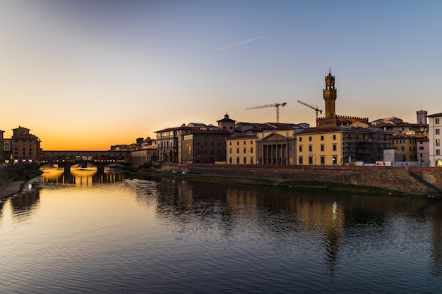Panoramiczny widok na słynny Ponte Vecchio z rzeką Arno o zachodzie słońca we Florencji, Włochy