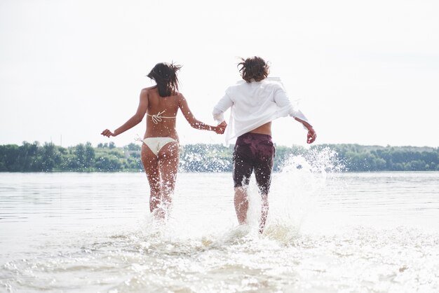 Para biegnąca wzdłuż wody, piękna letnia plaża.
