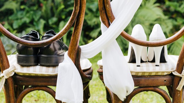 Para butów ślubnych na drewnianym krześle w parku