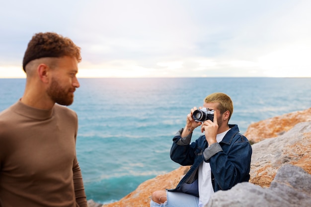 Bezpłatne zdjęcie para gejów na plaży z aparatem