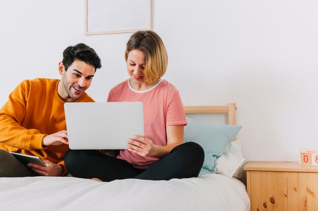 Para patrzeje laptop w łóżku