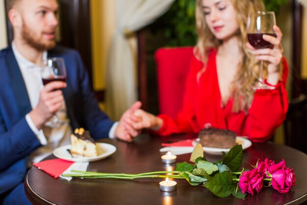 Para pije wino i trzyma ręki przy stołem