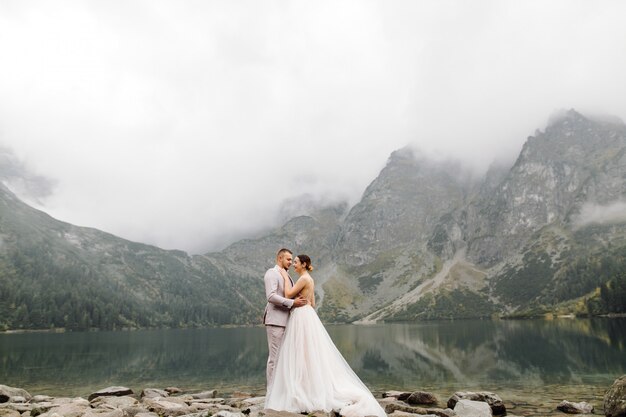 Para romantyczny ślub zakochany stojący nad jeziorem Sea Eye w Polsce. Tatry