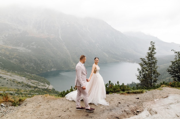 Para romantyczny ślub zakochany stojący nad jeziorem Sea Eye w Polsce. Tatry