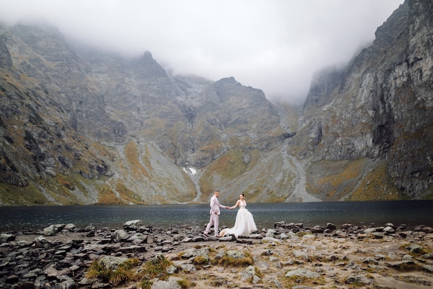 Para romantyczny ślub zakochany stojący nad jeziorem Sea Eye w Polsce. Tatry