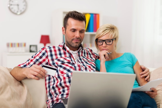 Para siedzi na kanapie w domu i płacąc rachunek on-line
