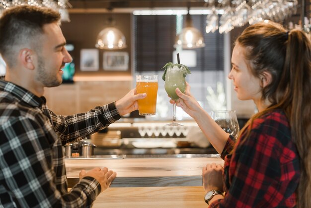 Bezpłatne zdjęcie para siedzi w barze podnosząc toast