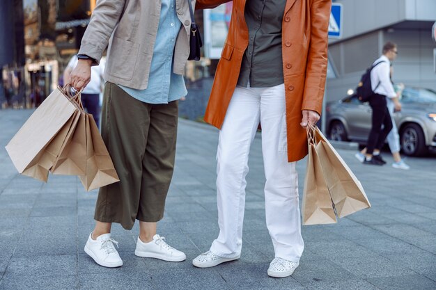 Para starszych pań trzyma torby na zakupy stojące na nowoczesnej ulicy miasta