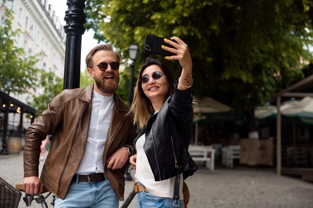 Para ubrana w kurtki ze skóry syntetycznej, robiąca selfie razem na zewnątrz