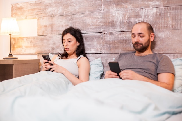 Para ubrana w piżamę i korzystająca z telefonów przed snem.