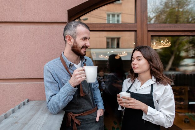 Para w fartuchach korzystających z kawy na zewnątrz