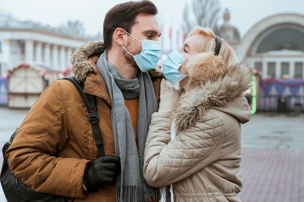 Bezpłatne zdjęcie para w zimie na sobie maski medyczne i przytulanie